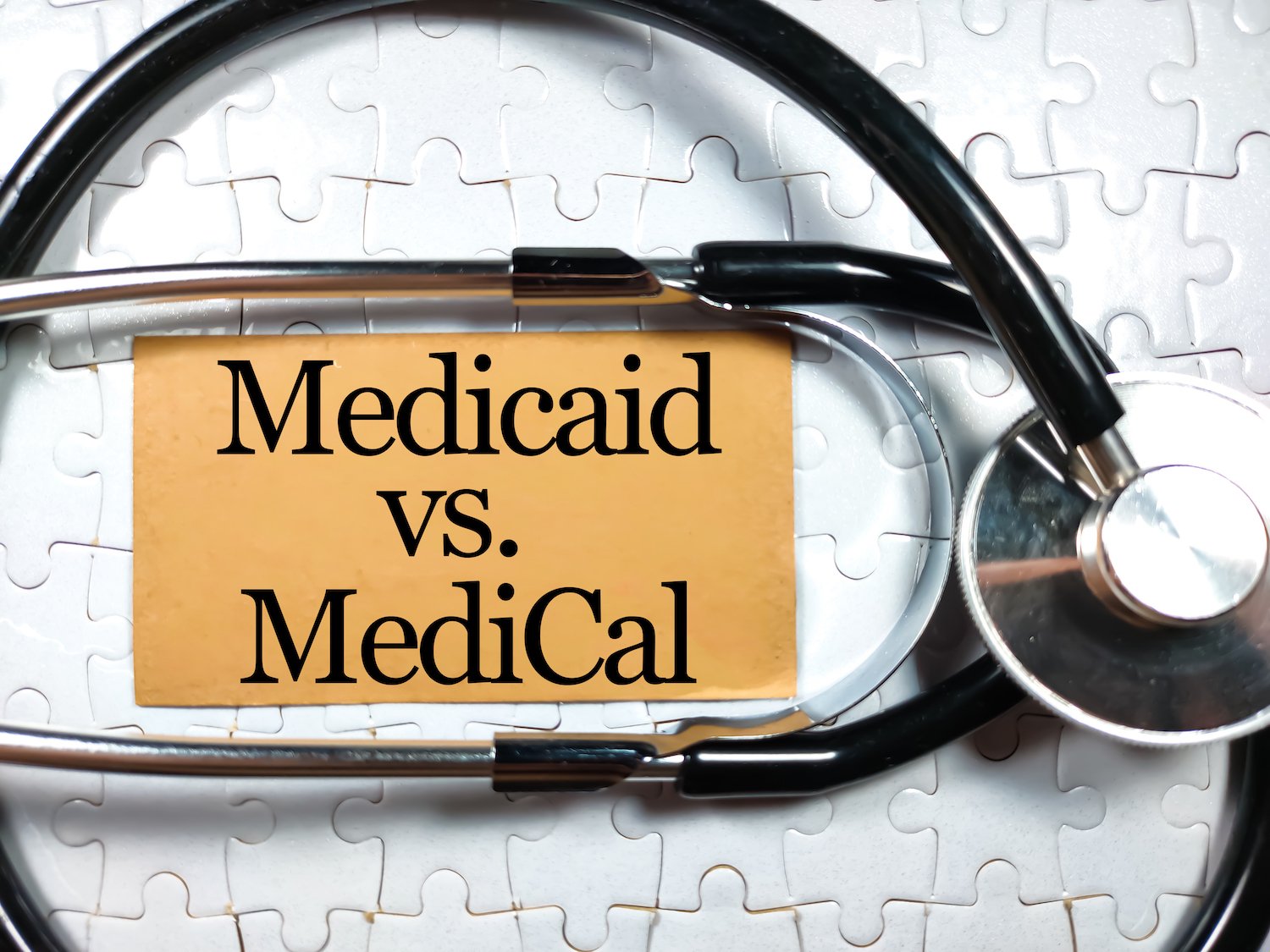 Medical concept.Text MEDICAID VS MEDICARE with stethoscope on white jigsaw puzzle background